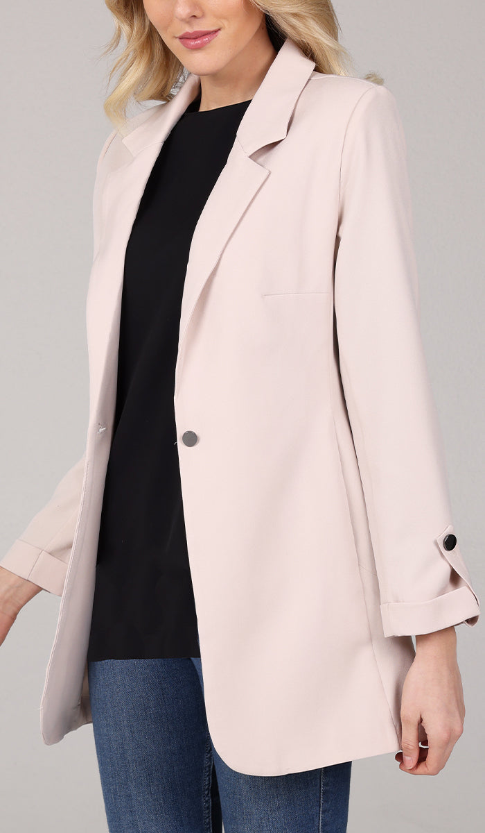 Close up view of woman wearing a cream blazer jacket with black top inside.