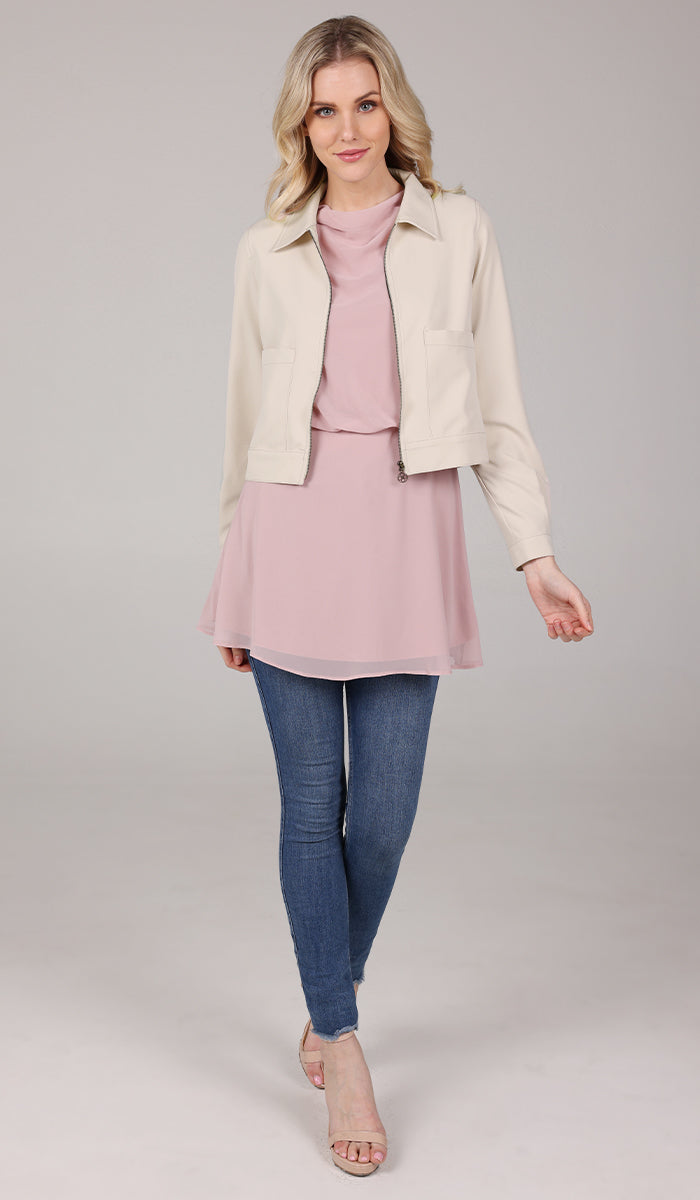 full view of a woman wearing a cream cropped jacket with a blush top.