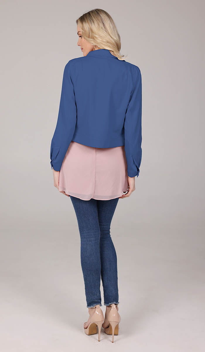 back view of woman wearing a blue cropped jacket, blush top and blue jeans.