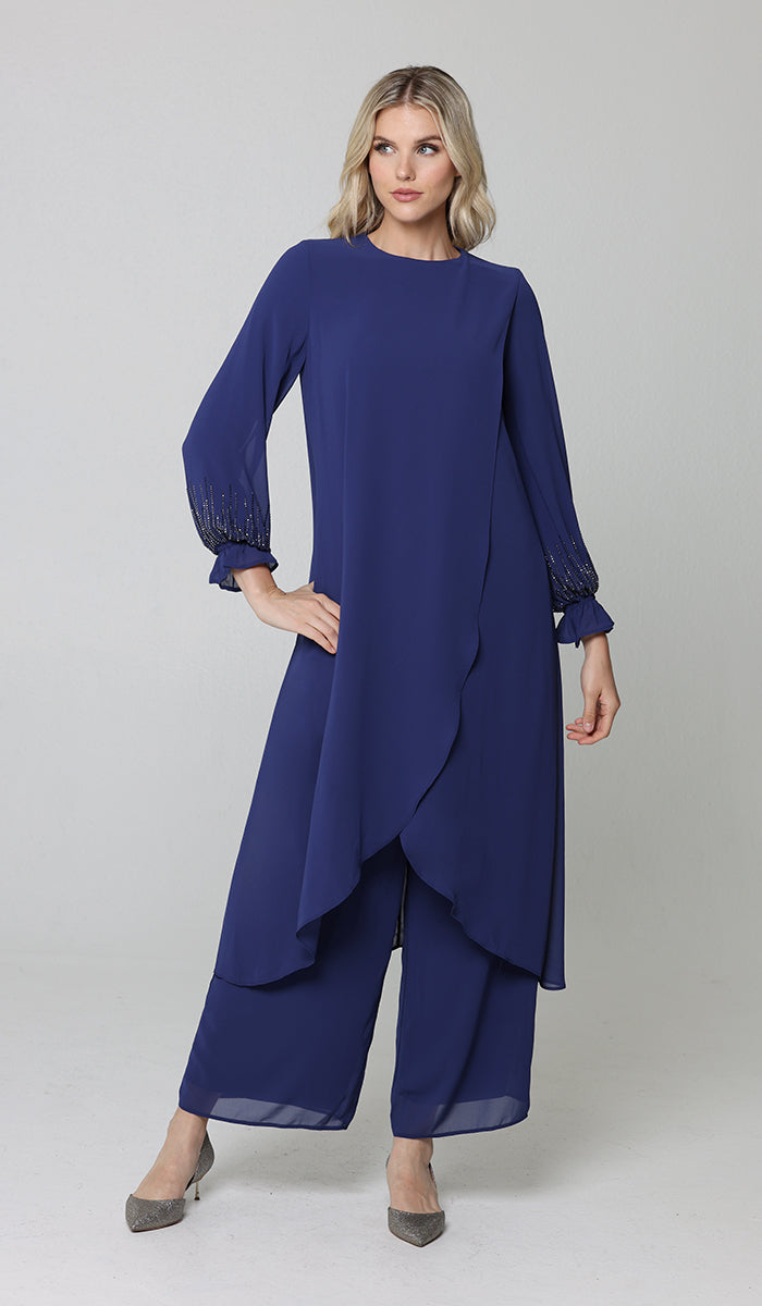 Model posing wearing Safa tunic and pants in blue. 