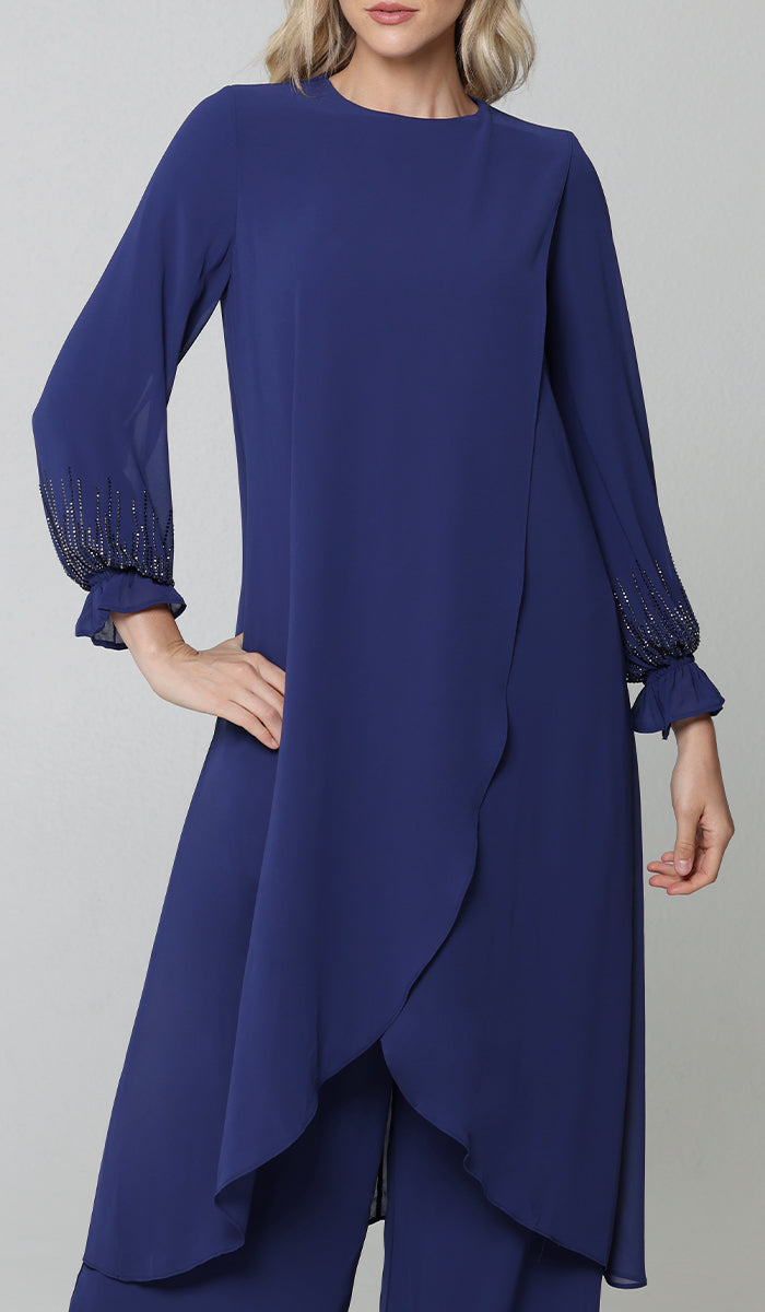 Model wearing blue Safa tunic with embellishment at the wrists. 