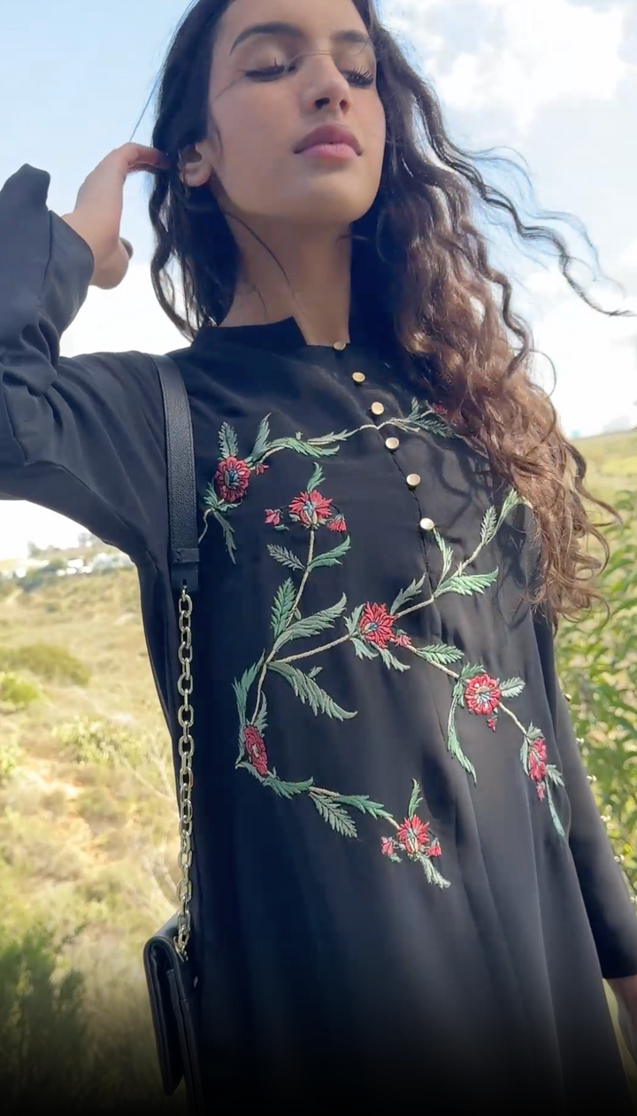 Brunette woman outside wearing embroidered Uzma tunic in Black. 