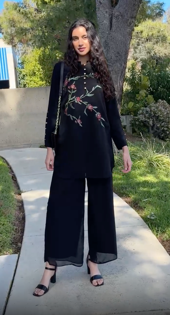 Woman outside wearing modest Uzma tunic in Black with Black pants, sandals, and purse. 