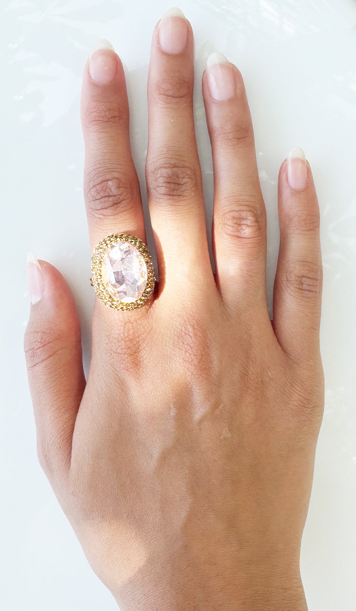 Hand wearing pink oval ring.