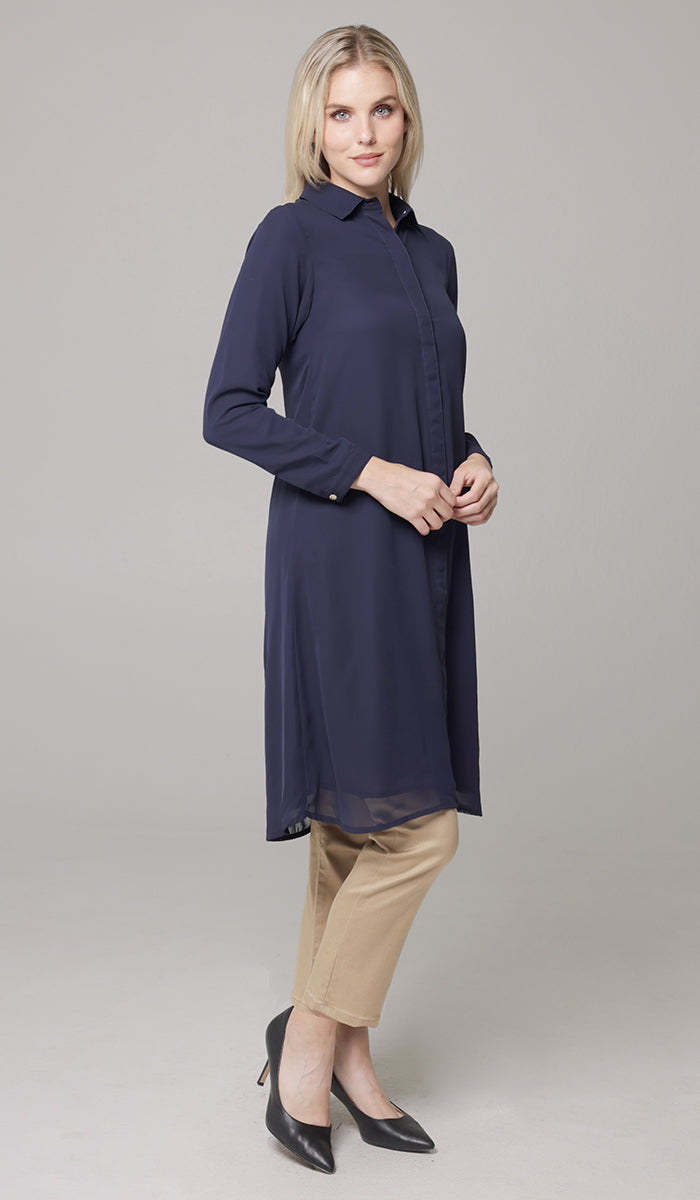 Side view of woman wearing Asra tunic in Navy with khaki pants and heels. 