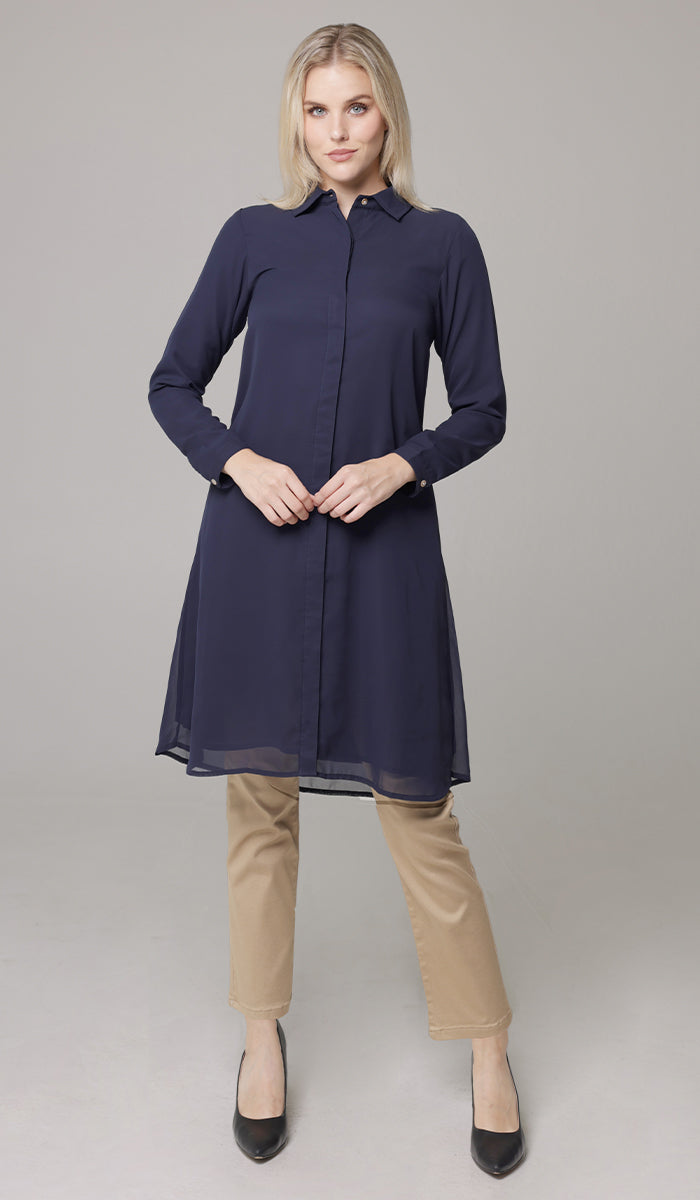 Woman wearing Asra buttondown tunic in Navy with khaki pants and heels. 