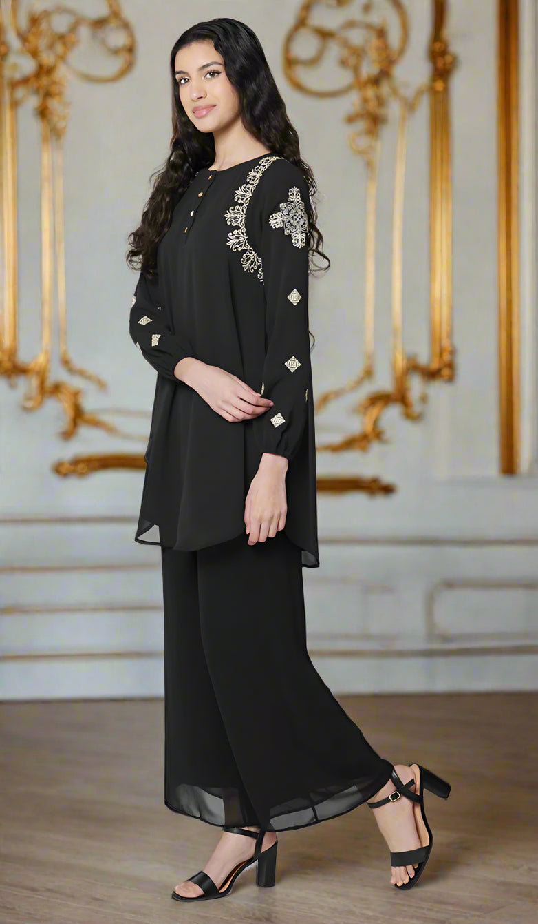 Woman turned to the side wearing Azmi tunic in Black with black pants and heels.