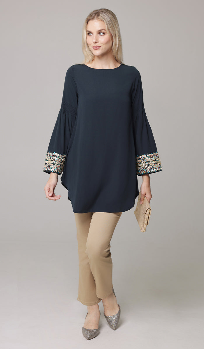 Woman looking to the side wearing Esme tunic in Dark Teal with Erem pants and heels. 