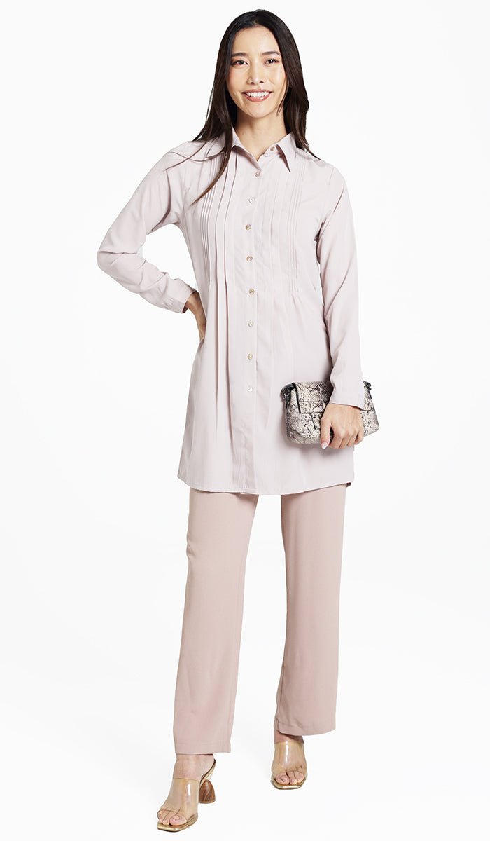 Woman wearing Hanane pleated button down in Blush with khaki pants and heels. 