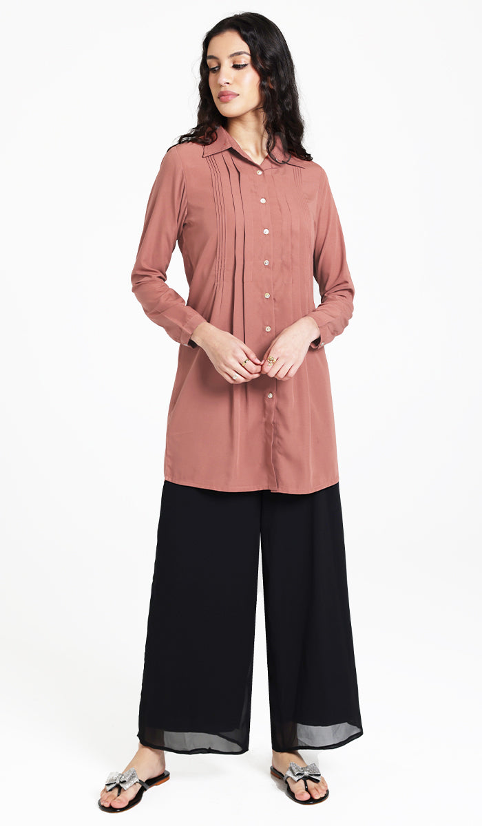 Woman wearing Hanane tunic in Rose with black pants and sandals. 