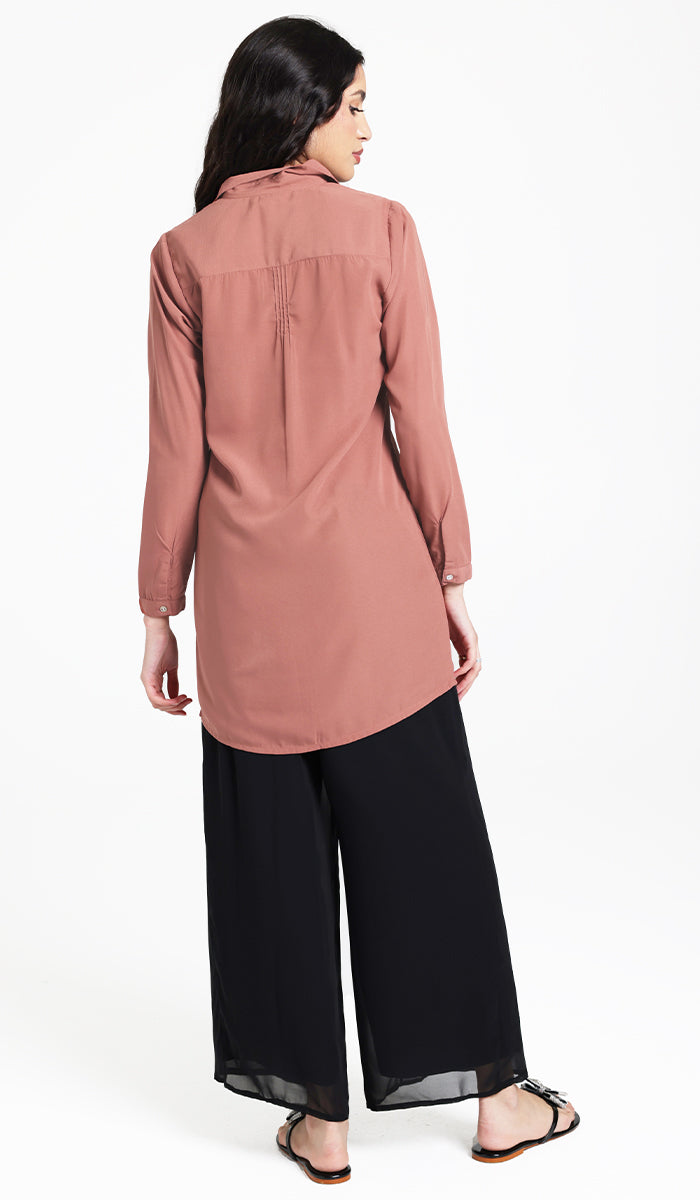 Back view of Hanane tunic in Rose with black pants and sandals. 