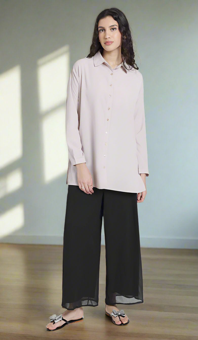 Front full view of female model wearing a blush Hania boxy button down with black wide leg pants. 