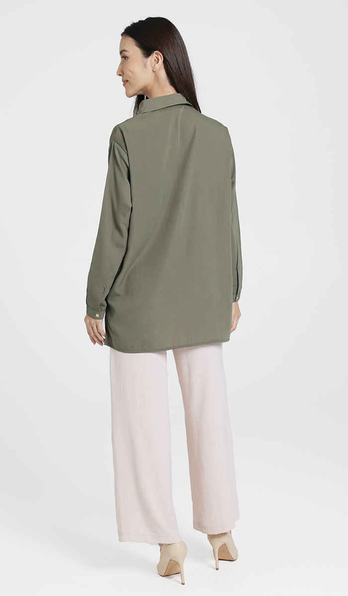 Back full body view of female model wearing an olive boxy button down and cream wide leg pants. 