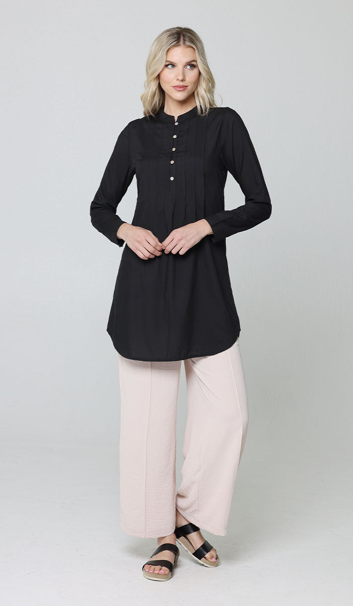 Woman smiling with arms crossed in front of her wearing Hurin tunic in Black with Cream Tina pants and sandals. 