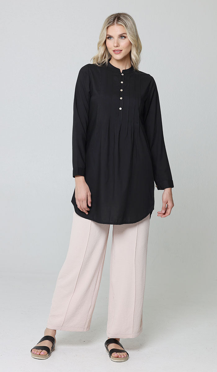 Full body image of woman wearing modest Hurin tunic in Black with Tina pants in Cream and black sandals. 