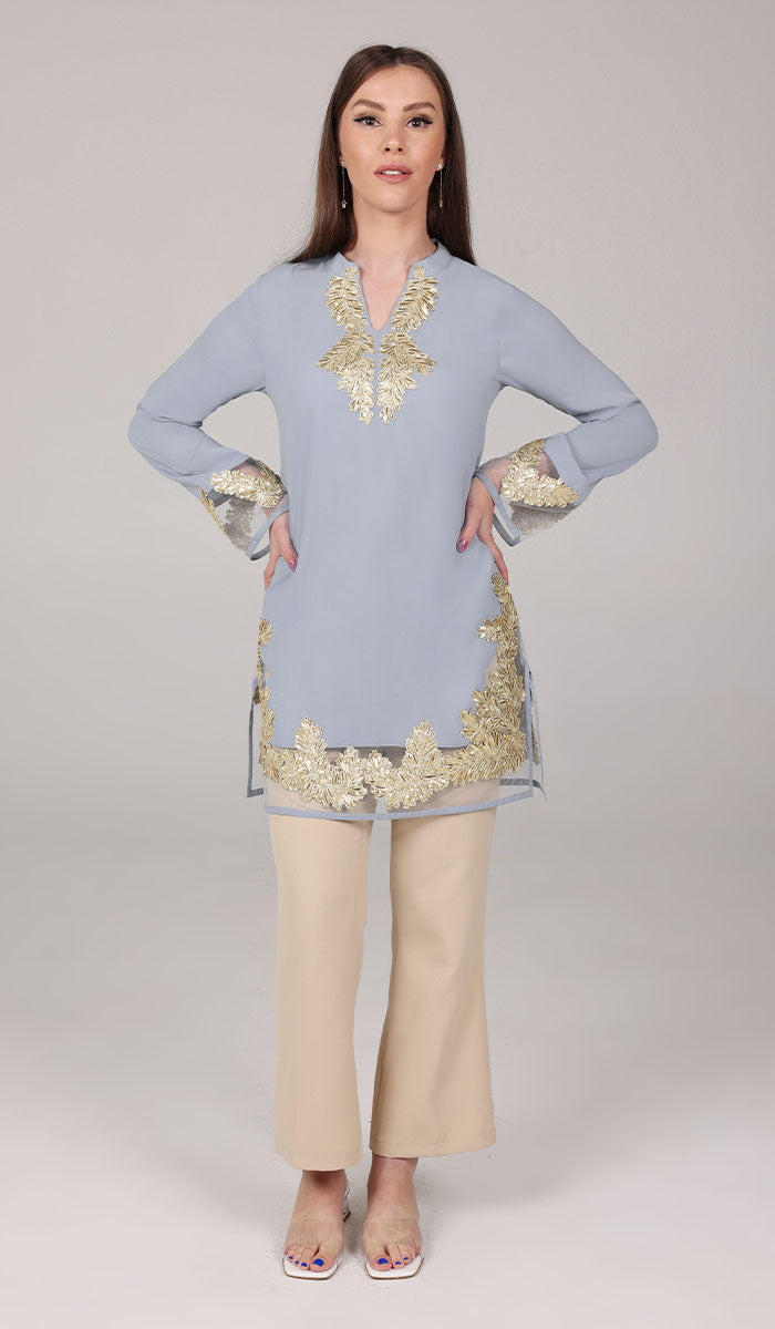 Woman wearing Mahnaz tunic in Silver Mist with khaki pants and heels. 