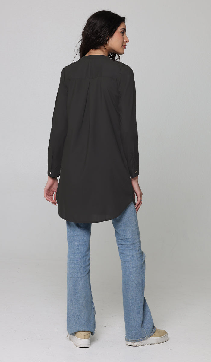 Back view of woman wearing Parisa tunic in Black with jeans and sneakers. 