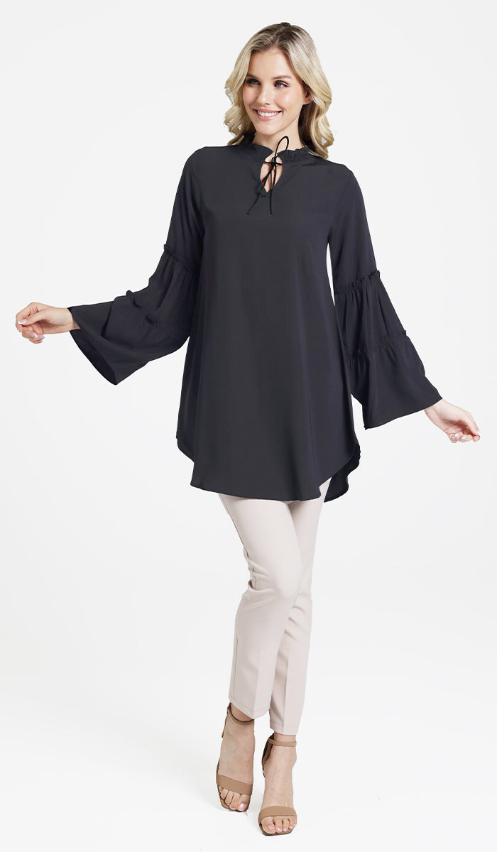 Smiling blonde woman wearing modest Saba tunic in Black with Alma pants and heels. 