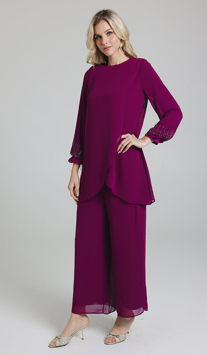 Three-quarter view of woman wearing Seema tunic in Orchid with pants and heels. 