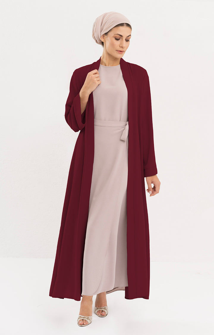 Woman with beige turban wearing a maroon duster jacket with a mocha dress.