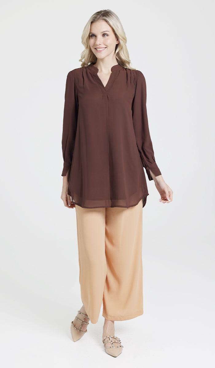 Full body side view of model wearing a brown chiffon Shaina top with light orange Ula pants in a different pose.