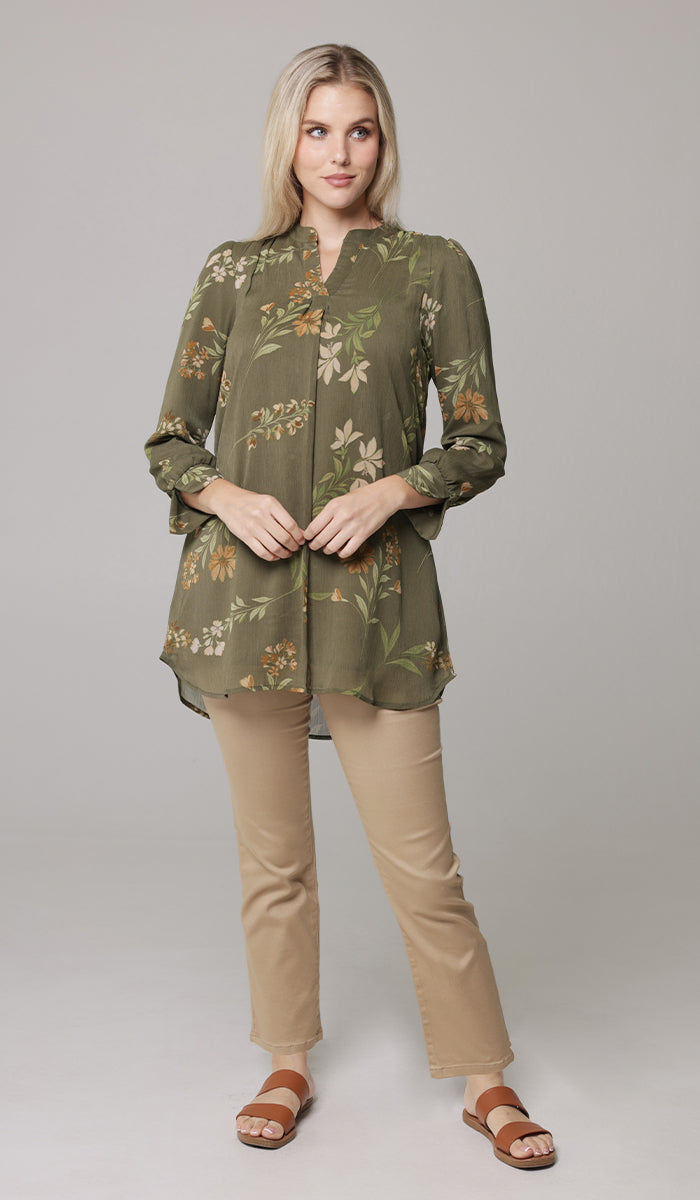 Smiling woman wearing modest chiffon Shaina tunic in Olive with khaki pants and sandals. 