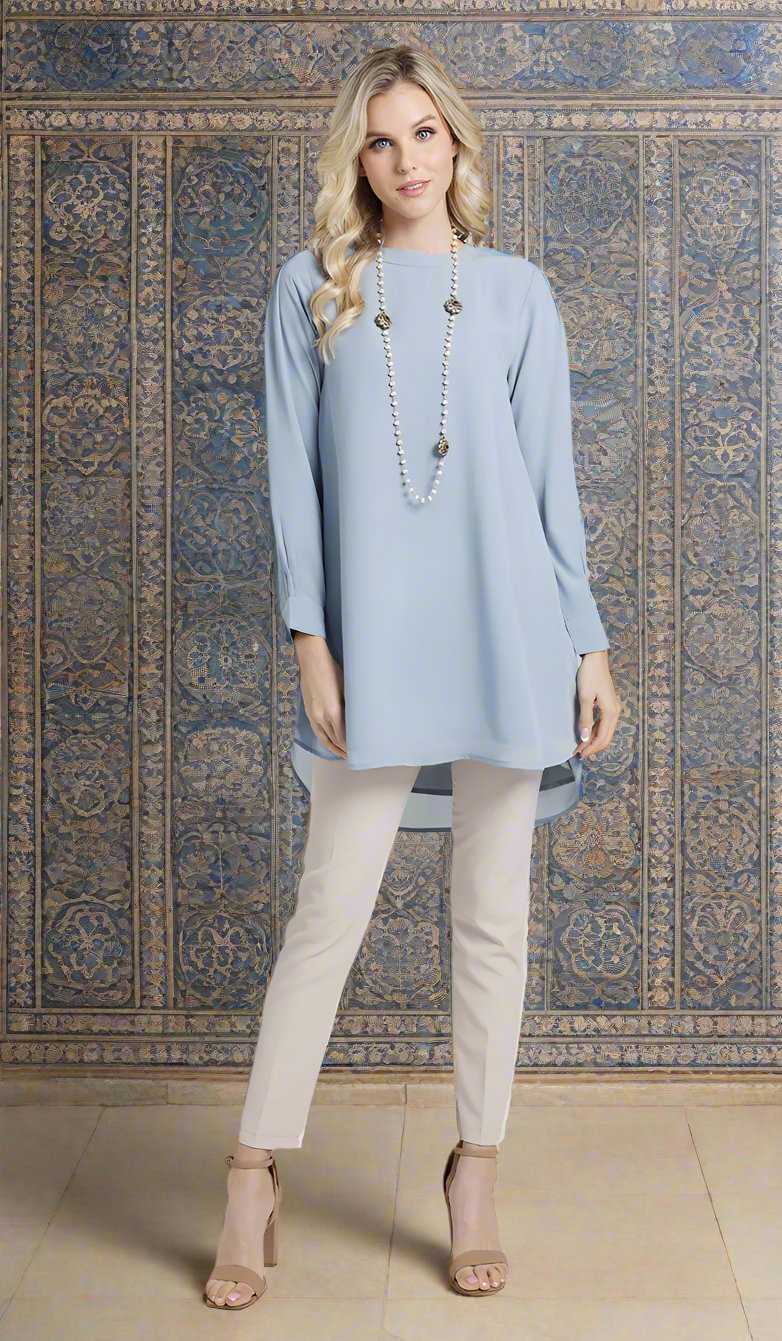 Woman wearing Sukoon tunic dress in Powder Blue with khaki pants and heels. 