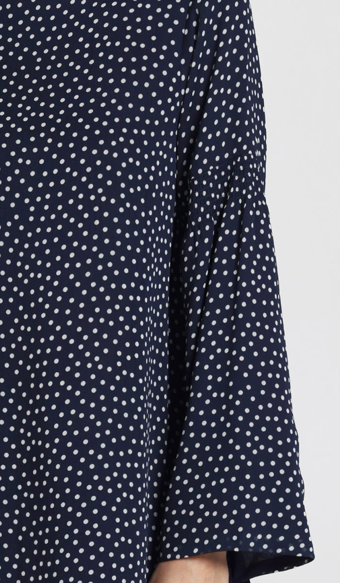 Up close details of bell sleeves and navy and white polka dot print. 