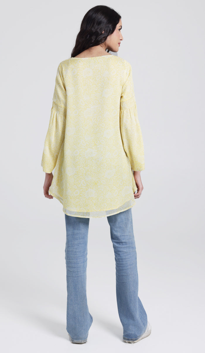 Back view of model wearing yellow modest tunic with jeans and sneakers. 