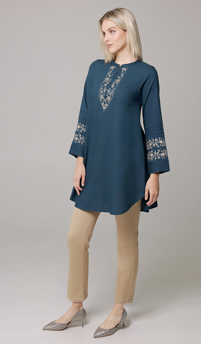 Woman looking to the side wearing Zoha tunic in Teal/Gold. 