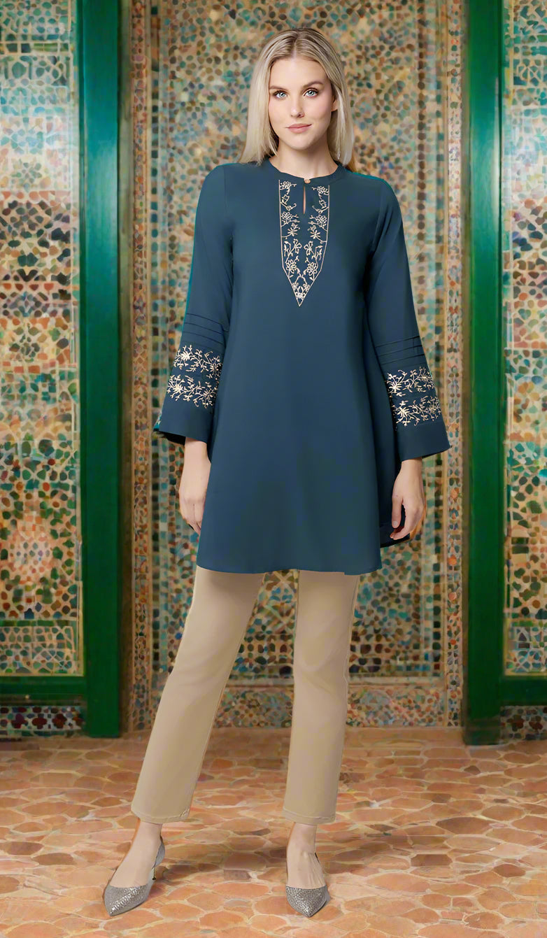 Woman wearing modest Zoha tunic in Teal/Gold with khaki pants and sparkly flats. 