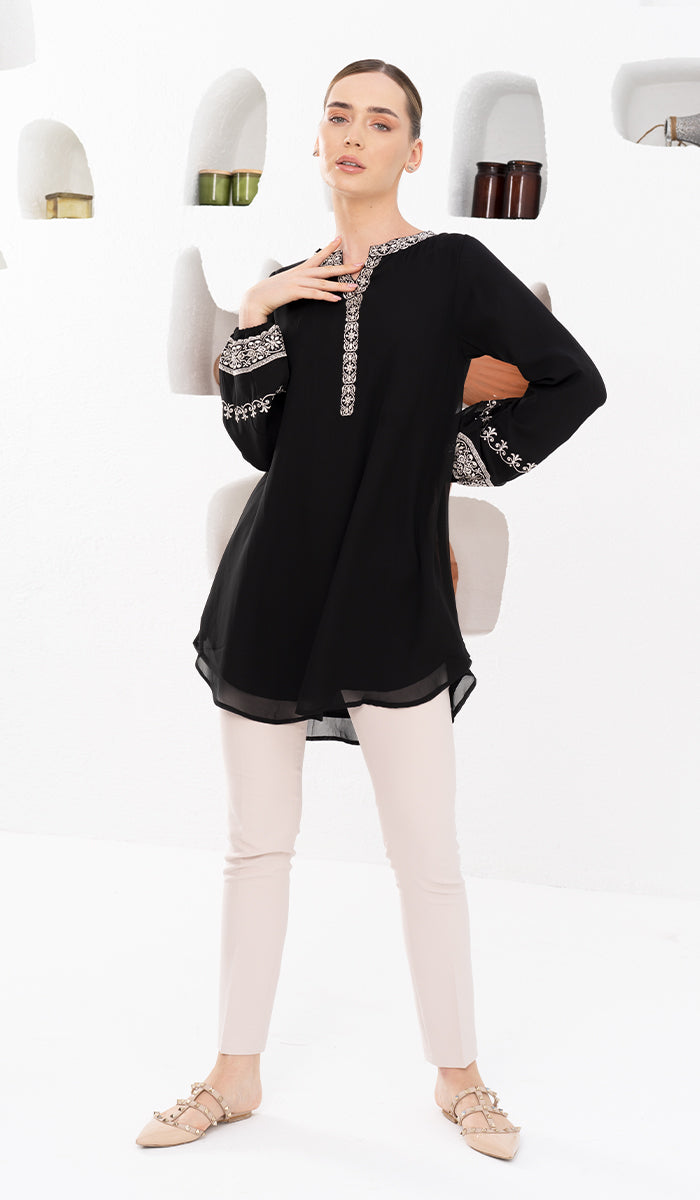 Model posed with hand on neck in modest Amalie tunic in Black. 