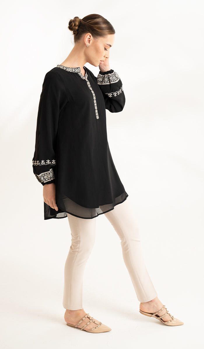 Side view of model wearing black Amalie tunic with khaki pants and flats. 