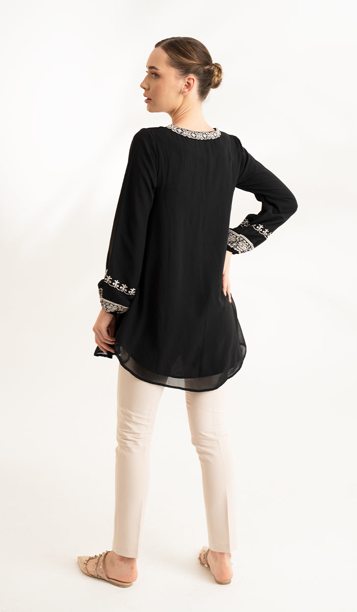 Back view of black modest Amalie tunic, paired with khaki pants and flats. 