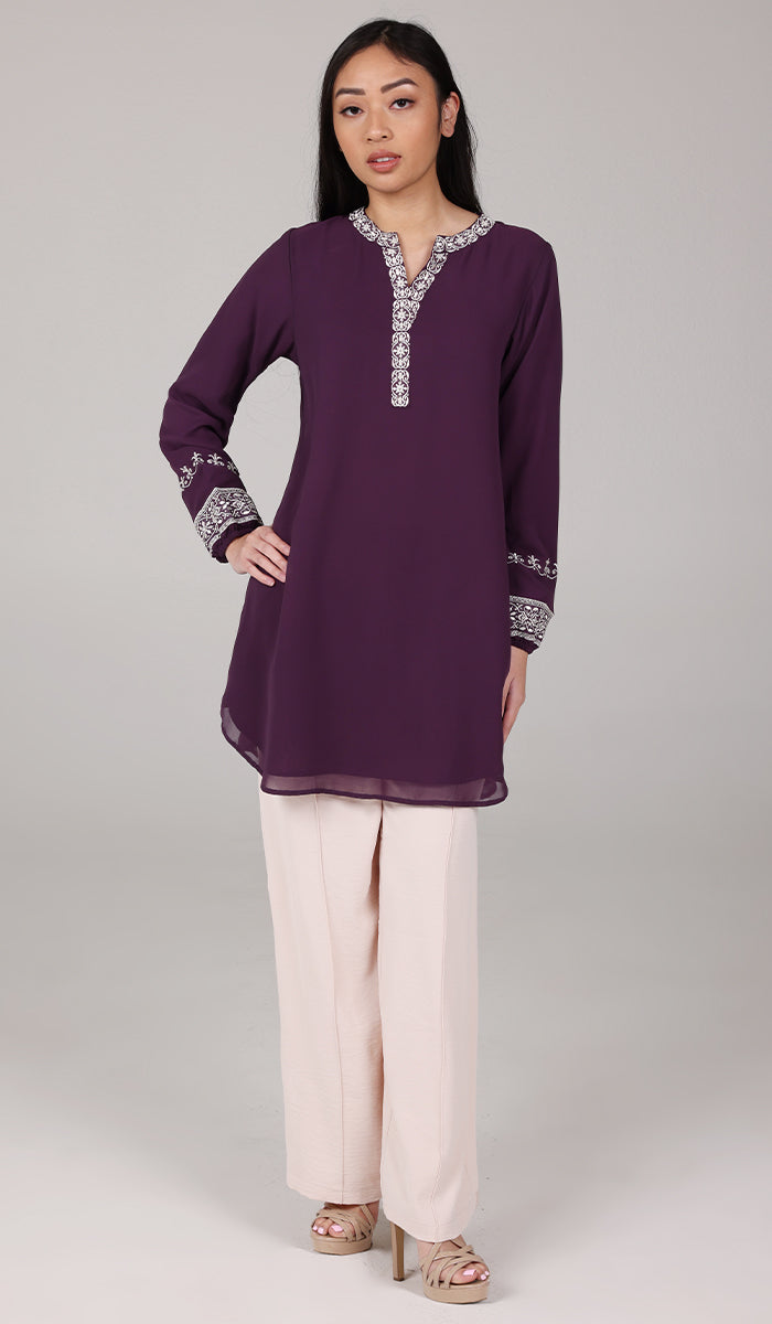 Woman wearing modest Amalie tunic in Eggplant with white pants and heels. 