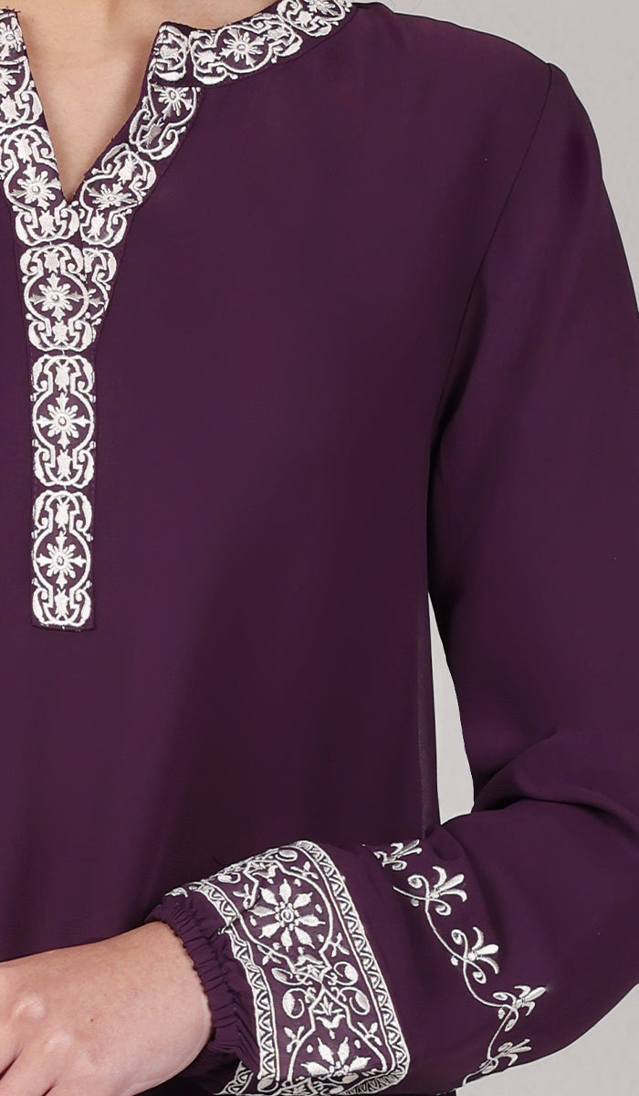 Embroidery detail of woman wearing Amalie tunic in Eggplant. 