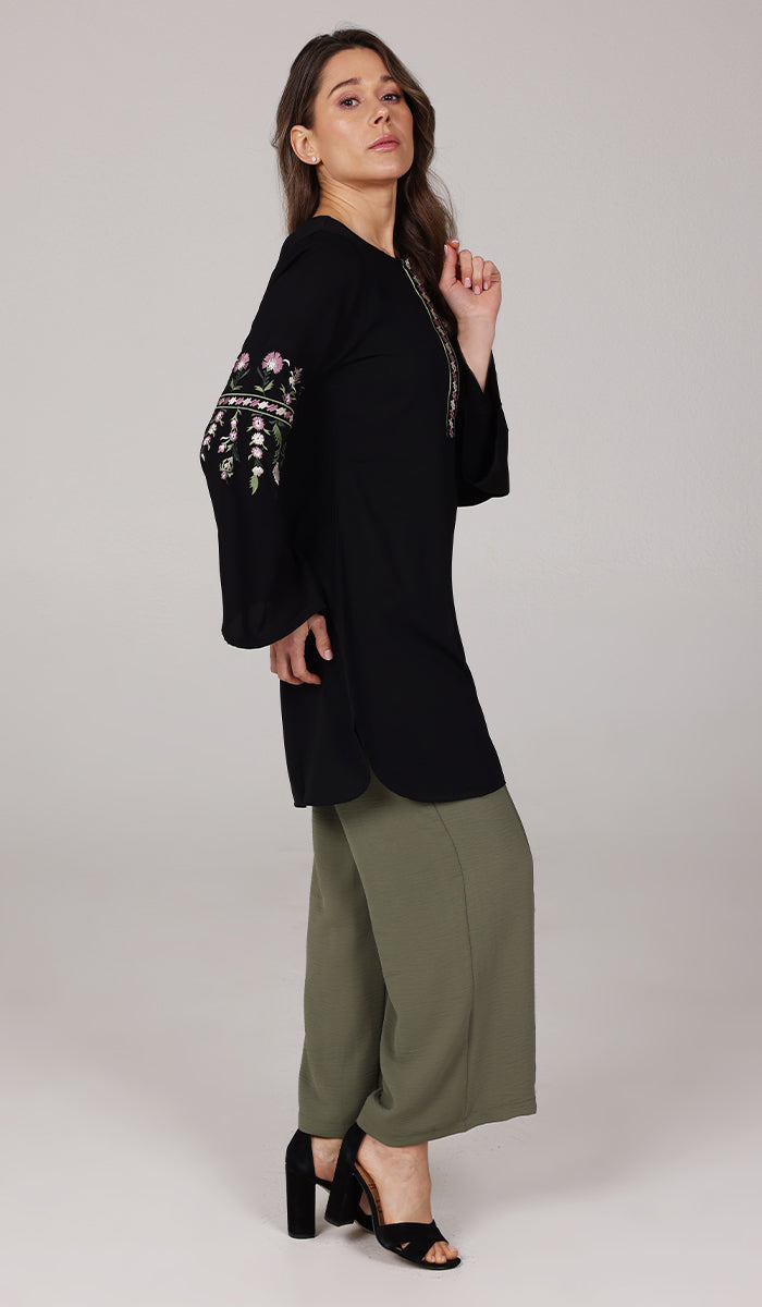 Side view of model wearing Gulzar tunic in Black with Olive Tina pants and black heels. 