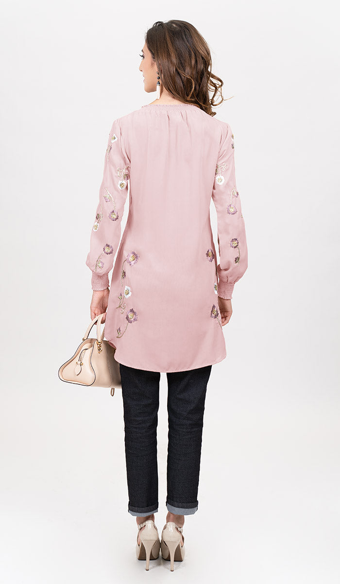 Back view of woman wearing Iman tunic in Blush Pink with jeans, heels, and a handbag.