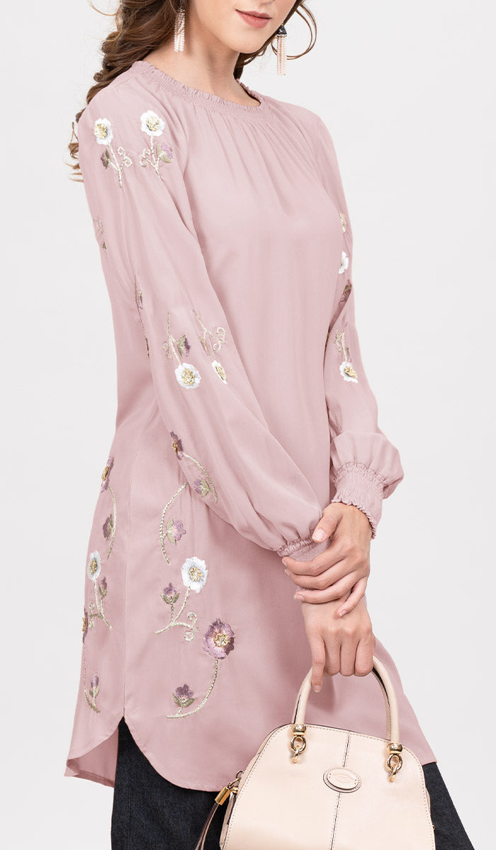 Side view of woman wearing Iman tunic in Blush Pink, holding a handbag.