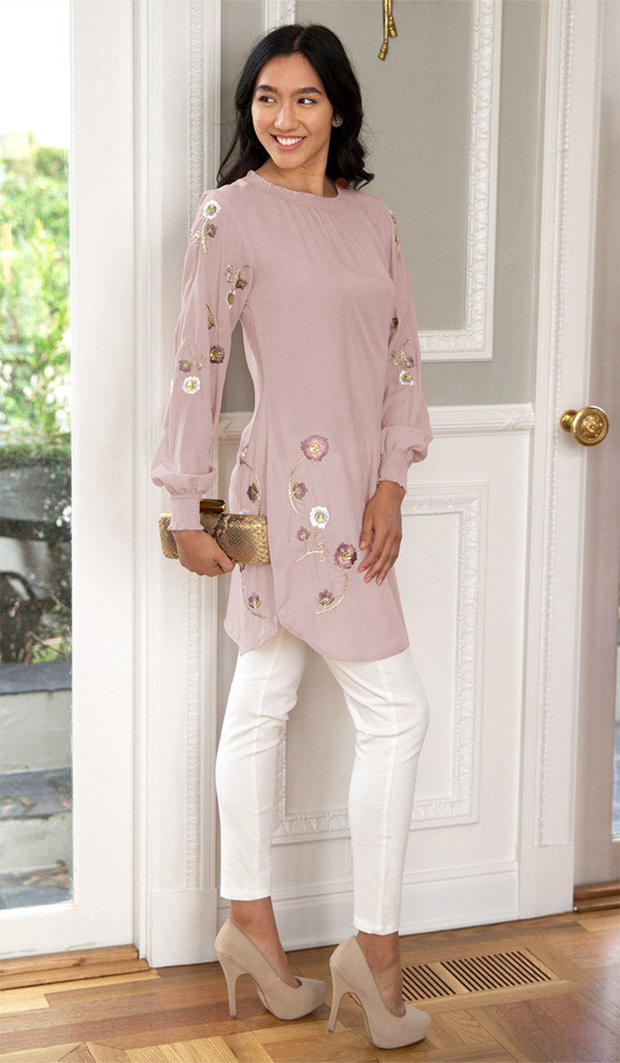 Side view of woman wearing Iman tunic in Blush Pink with white jeans, heels, and a handbag. 