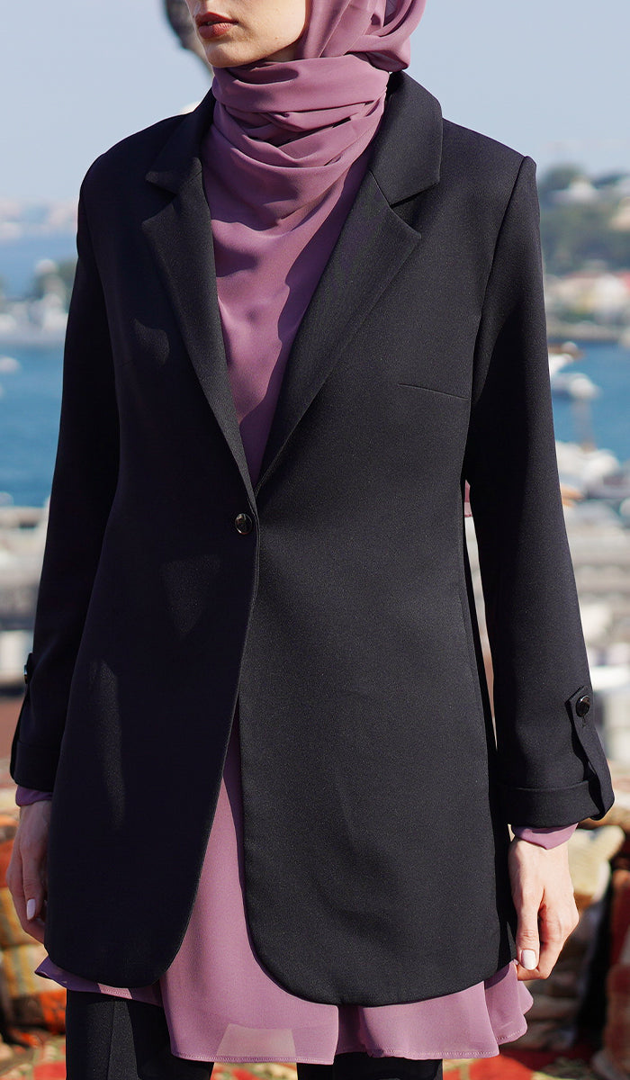 Close up of woman with dusty mauve hijab and top wearing a black blazer.