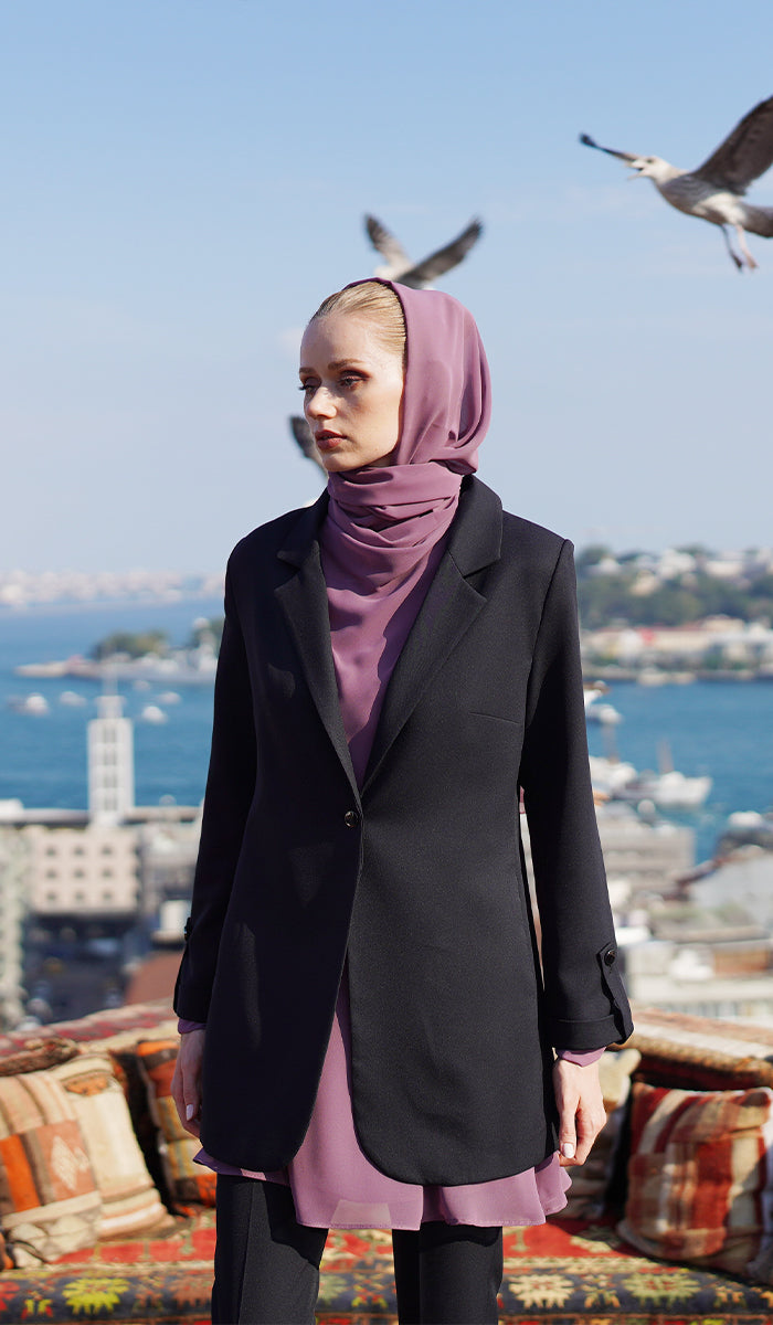 Woman with dusty mauve hijab and top wearing a black blazer and black pants.