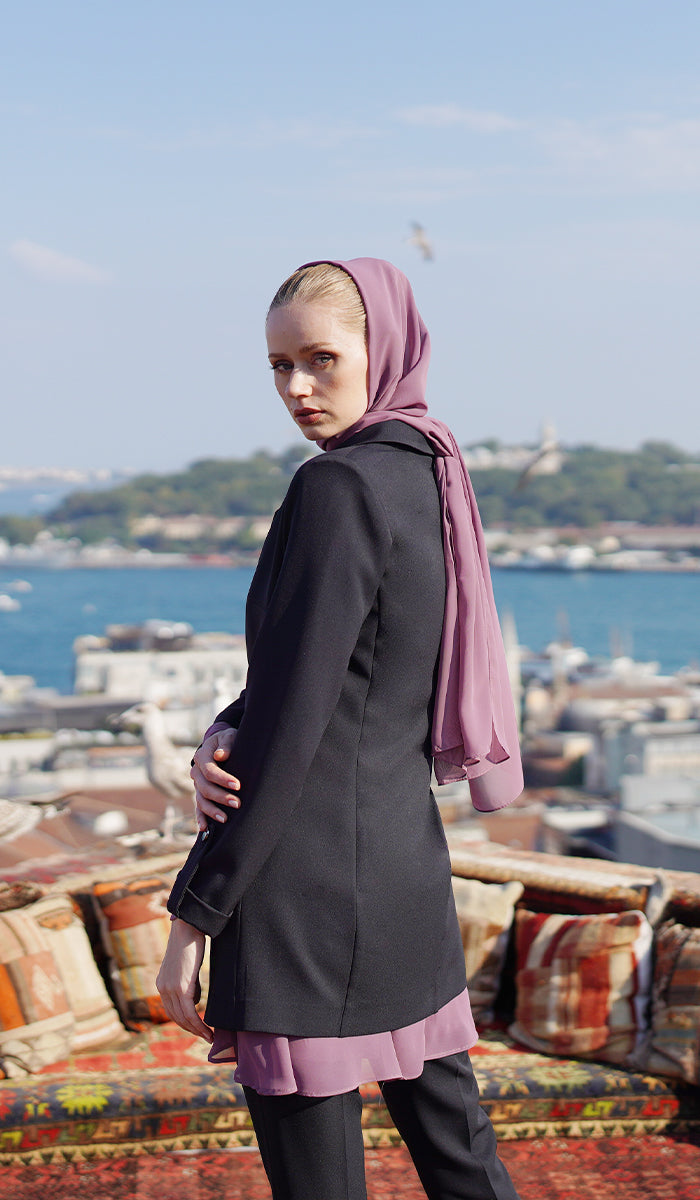 Back view of woman with dusty mauve hijab and top wearing a black blazer and black pants.