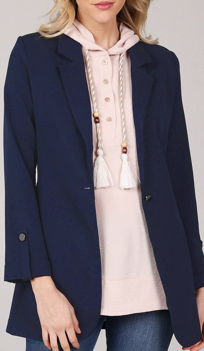 Close up of woman wearing a cream hoodie inside a navy blue blazer.