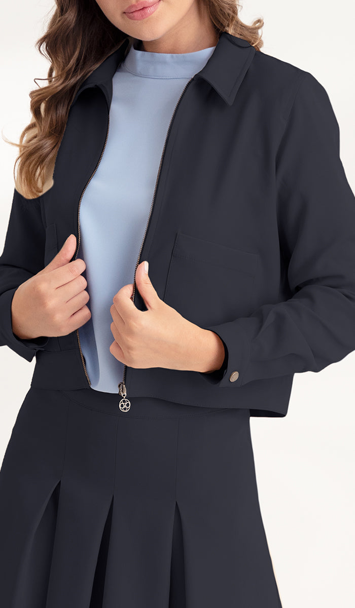 close up view of woman wearing a crop black jacket with black pleated skirt.