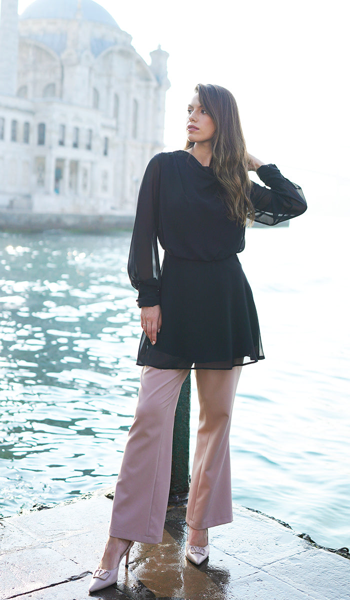 Woman by the water wearing chiffon Myra tunic in Black. 