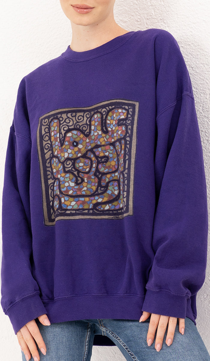 close up view of woman wearing a purple pullover with square design.